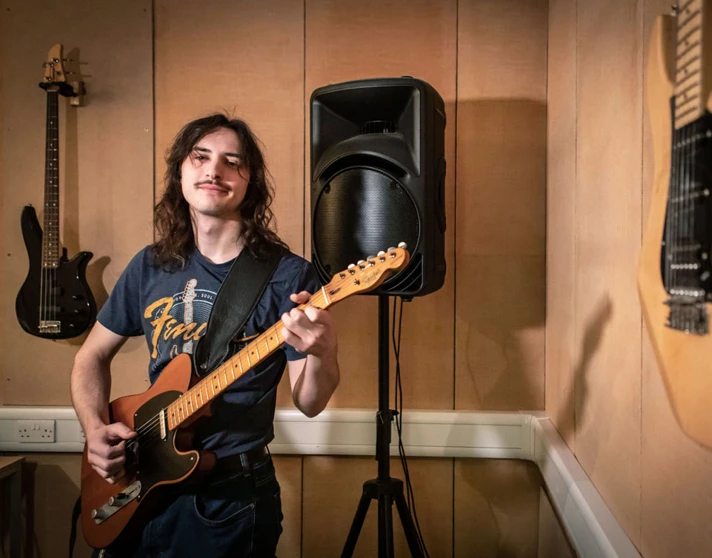 A guitarist wearing a Fender t-shirt playing an electric guitar. A guitarist wearing a Fender t-shirt playing an electric guitar.